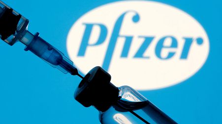 A vial and syringe are seen in front of a displayed Pfizer logo in this illustration taken January 11, 2021