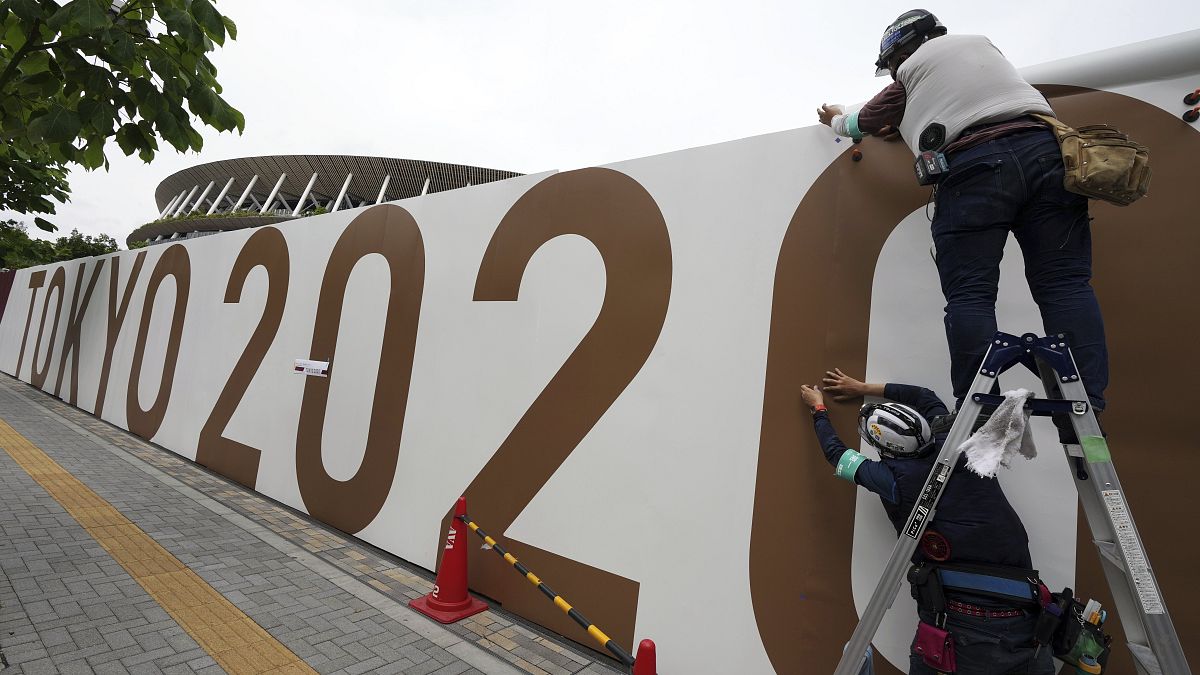 Munkások dekorálják a tokiói új Nemzeti Stadion körüli kerítést Tokióban 2021. június 1-jén.