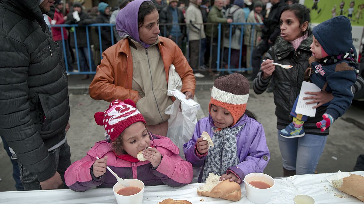 FILE - In this Wednesday, Dec. 16, 2015 file photo, homeless children eat as others wait in line for their turn outside the main railway station in Bucharest, Romania. 