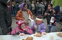 FILE - In this Wednesday, Dec. 16, 2015 file photo, homeless children eat as others wait in line for their turn outside the main railway station in Bucharest, Romania.