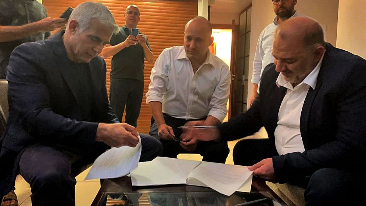 head of the Arab Israeli Islamic conservative party Raam Mansour Abbas (R) signing a coalition agreement with Israel's opposition leader Yair Lapid 