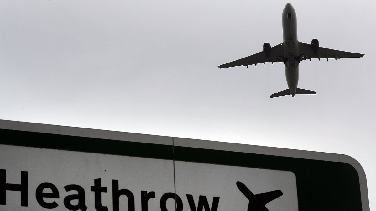 A plane takes off over a road sign near Heathrow Airport in London.