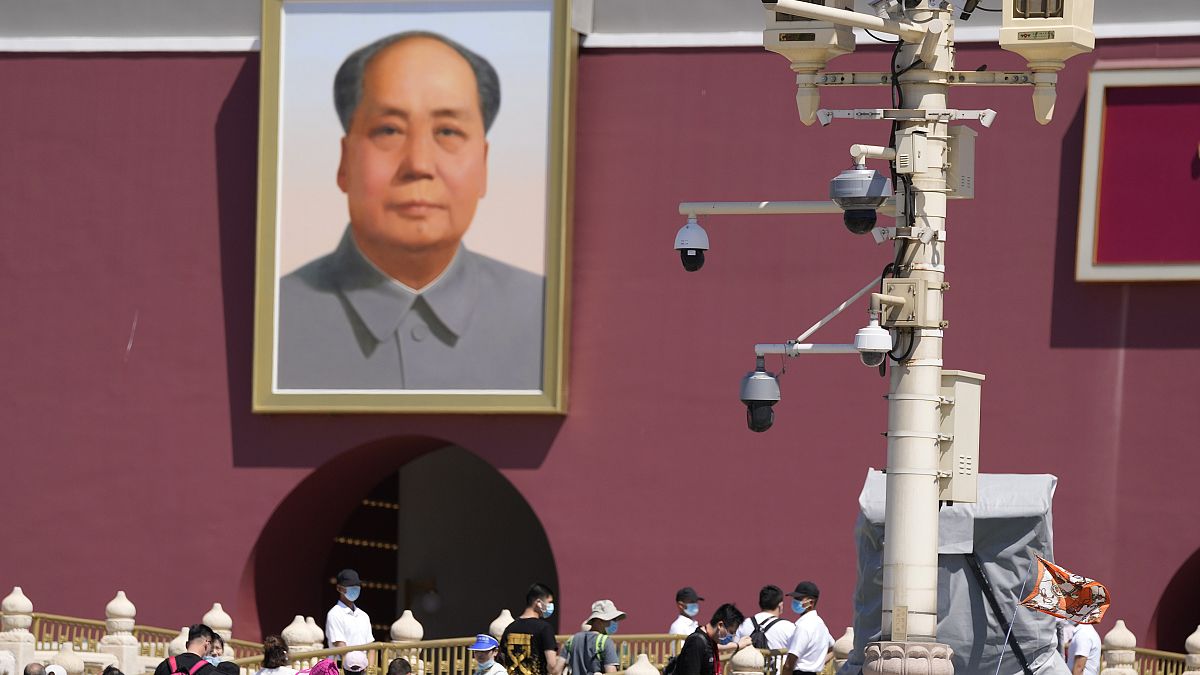 With surveillance cameras seen on a pole, plainclothes security personnel watch as tourists visits Tiananmen Gate on the 32nd anniversary of a deadly crackdown on protest.