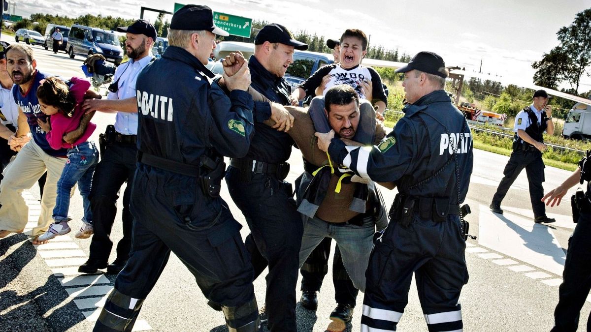 n this Sept. 9, 2015 file picture police grab a refugee as hundreds of refugees walk in Southern Jutland motorway near Padborg in Denmark
