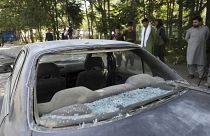 Afghan men look at a damage car after a roadside bomb explosion in Kabul, Afghanistan, Sunday, June 6, 2021.
