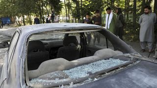 Afghan men look at a damage car after a roadside bomb explosion in Kabul, Afghanistan, Sunday, June 6, 2021.