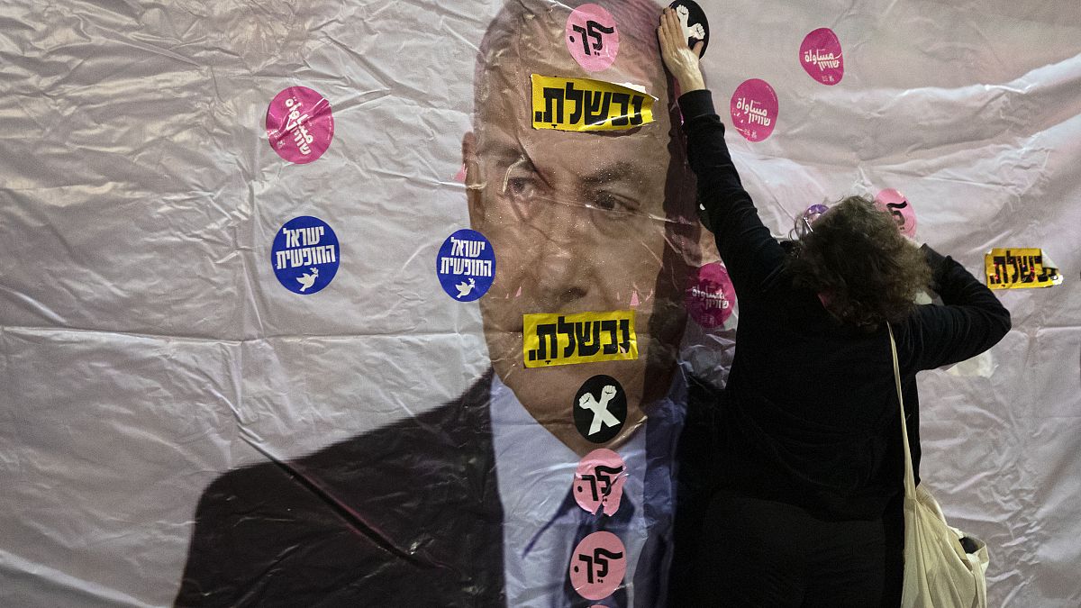 محتج إسرائيلي يضع ملصقا على صورة بنيامين نتنياهو خلال مظاهرة نظمت أمام منزله في القدس وقد كتب عليها بالعبرية: "لقد فشلت"، "ارحل". 2021/06/05