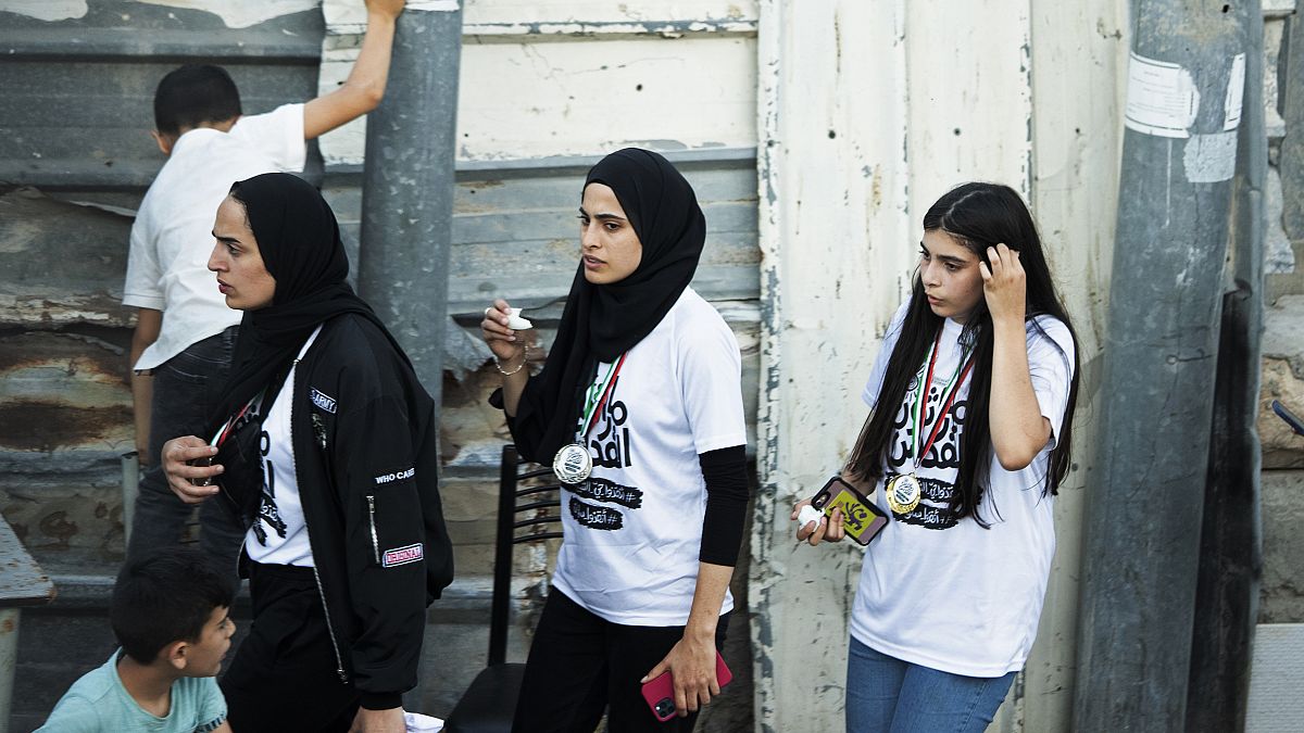In this Friday, June 4, 2021 photo, Palestinian activist Muna el-Kurd, centre, wears a medal from a marathon as she leaves the site where Israeli police fired tear gas.