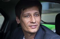 In this Tuesday, July 30, 2019 file photo, Russian opposition candidate Dmitry Gudkov speaks to journalists sitting inside a police car as he arrives to the court in Moscow.