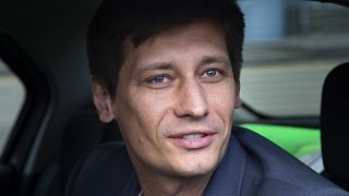 In this Tuesday, July 30, 2019 file photo, Russian opposition candidate Dmitry Gudkov speaks to journalists sitting inside a police car as he arrives to the court in Moscow.