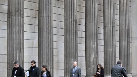 People walk past the Bank of England in the City of London's financial district 