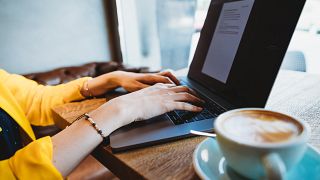 Digital nomad works on a laptop in a café.