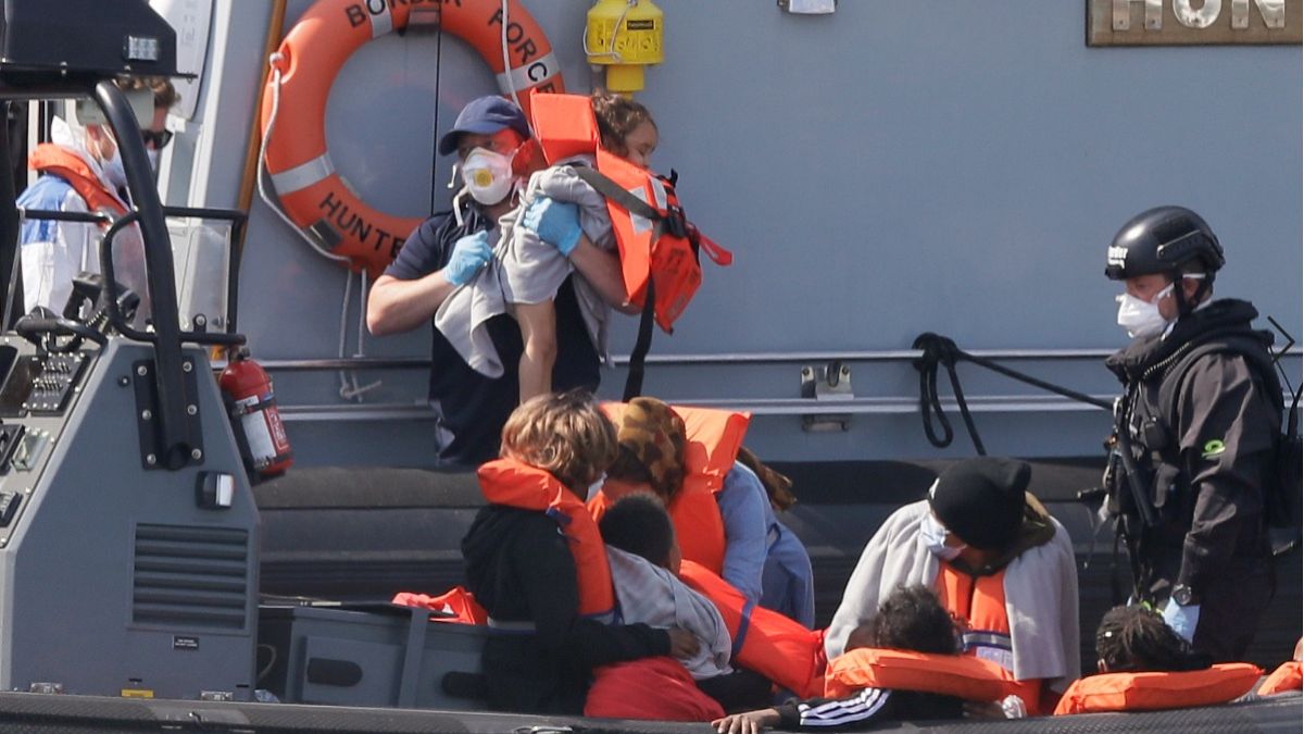 A Border Force official lifts a child from a small boat arriving in the port of Dover in August 2020
