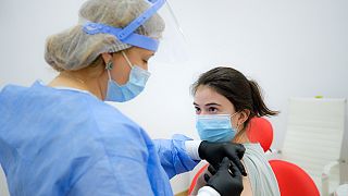 A woman gets an AstraZeneca vaccine at a vaccination center in Bucharest, Romania, Wednesday, April 7, 2021.