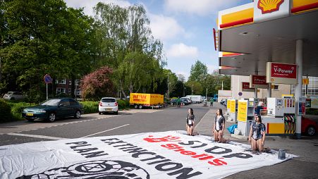 Protestors covered in black paint take part in an action called by global environmental movement Extinction Rebellion, at a Shell gas station in The Hague.