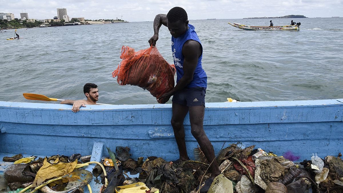 Mann sammelt Plastikmüll vor der Küste Senegals