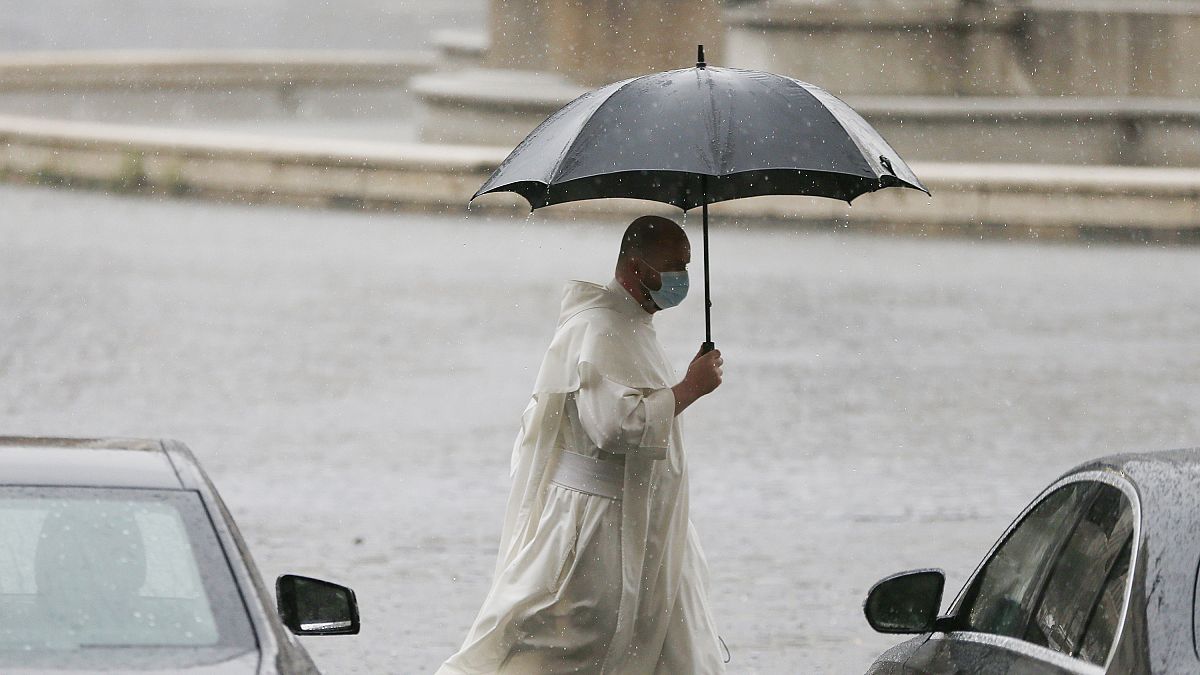 A priest is pictured walking through unusually heavy rainfall that hit Rome on Tuesday.