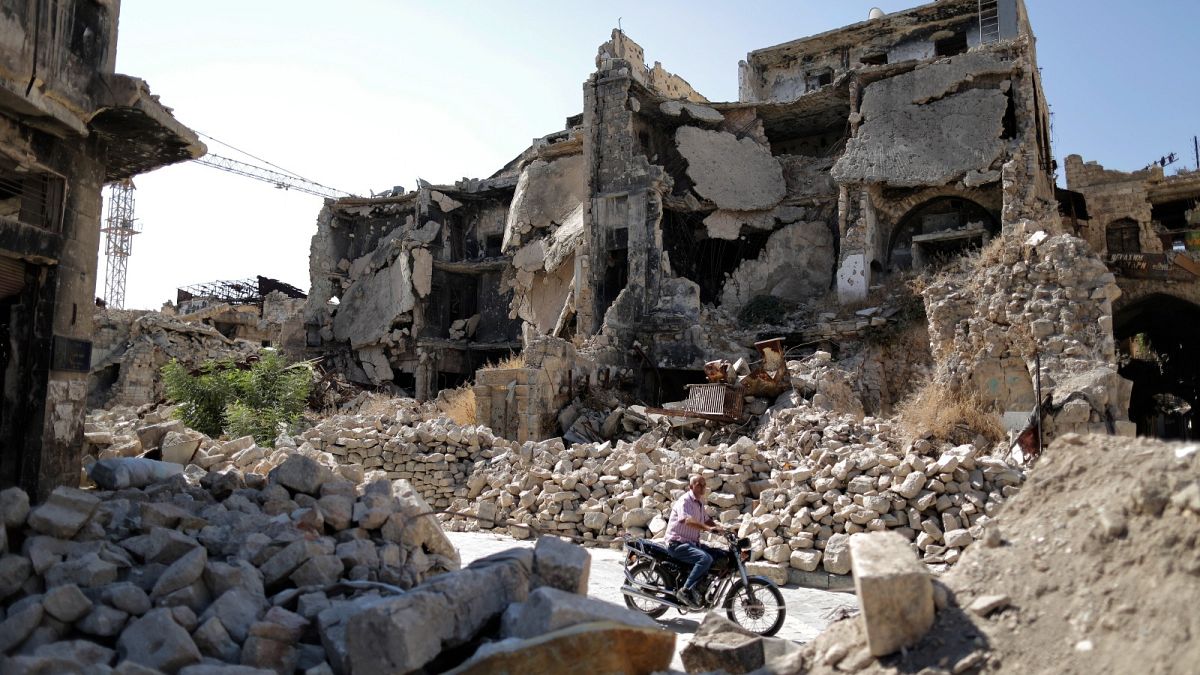 FILE: In this Saturday, July 27, 2019 photo, a man rides his motorcycle through the rubble of the old city of Aleppo, Syria. 