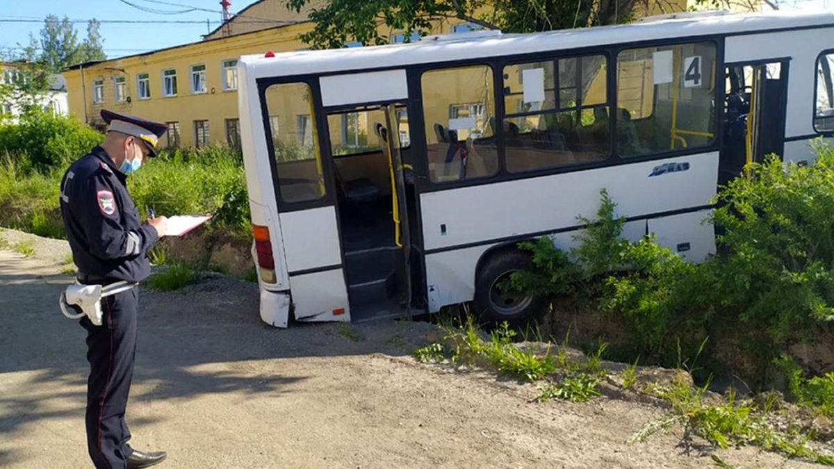A Russian police officer stands near the damaged bus.