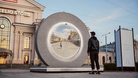 A young man stands in front of a one of two hi-tech 'portals' installed in Lulblin, Poland and Vilnius, Lithuania which give passers by a real-time look at life in each city,