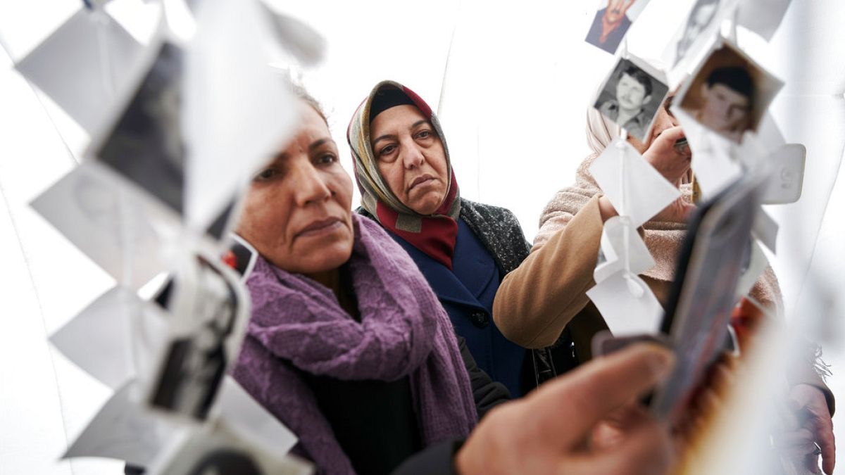 Women look at images of victims inside a traveling monument called 'Prijedor 92' outside the Yugoslav War Crimes Tribunal, ICTY