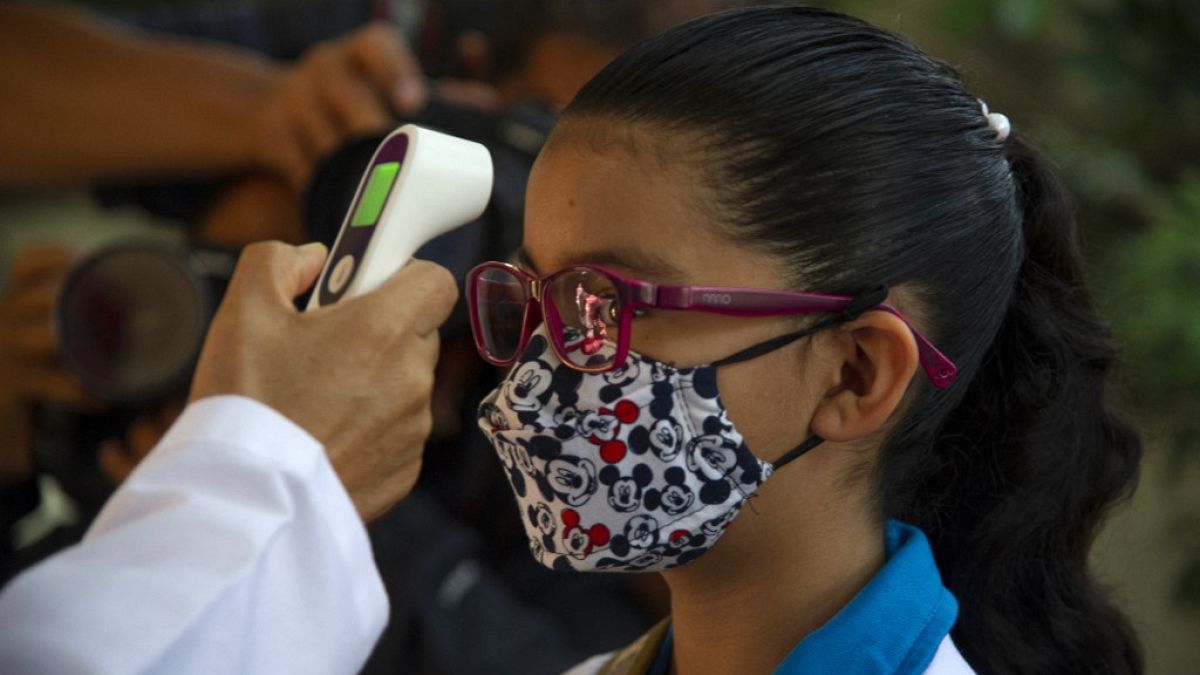 Meksika'da sınıfa girmeden önce ateşini ölçtüren kız çocuğu