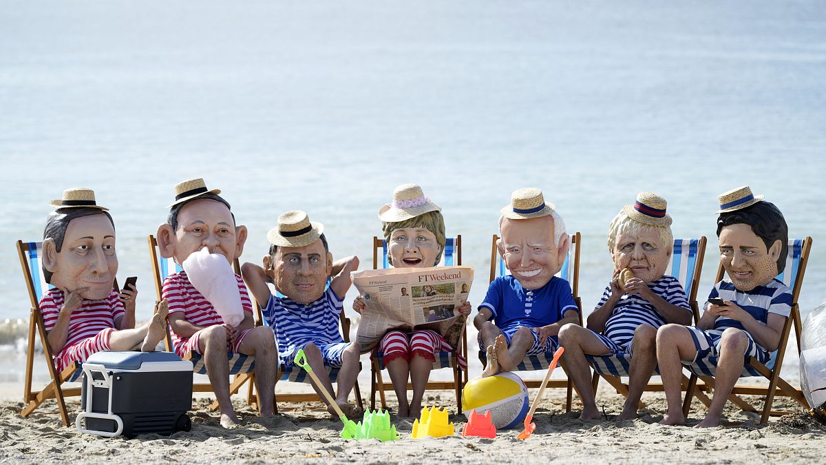 Activistas climáticos de Oxfam, con cabezas gigantes que representan a los líderes del G7 en la playa de Swanpool en Falmouth, Cornualles, Inglaterra, el 12 de junio de 2021.