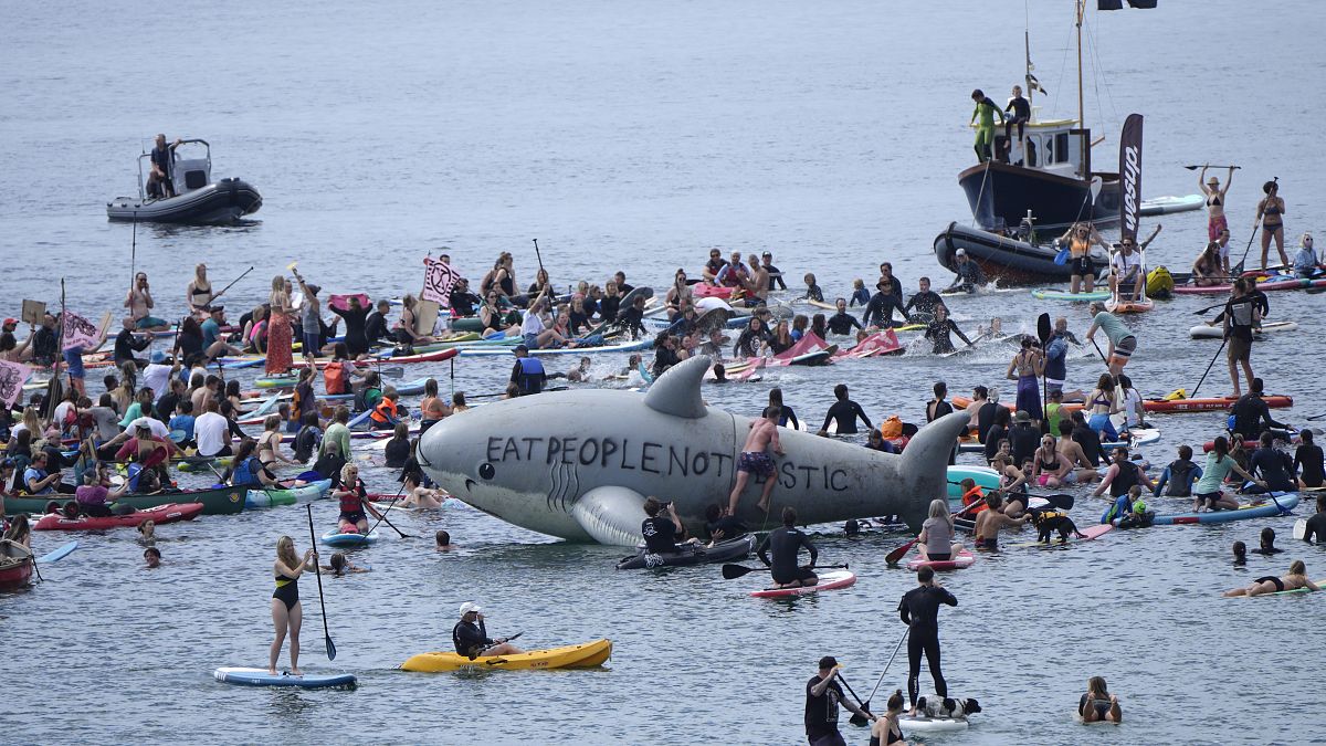 Paddleboarders and surfers take part in a paddle out to raise awareness for climate action in the sea at Gyllyngvase Beach in Falmouth, Cornwall, England, June 12, 2021.