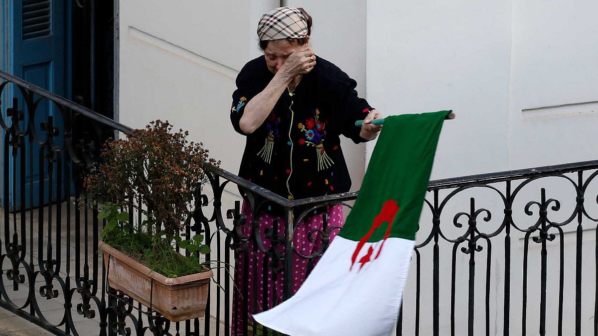 امرأة تمسح دموعها وهي تحمل العلم الوطني مع خروج المتظاهرين إلى الشوارع في العاصمة الجزائرية لرفض الانتخابات الرئاسية ، الجزائر، 27 ديسمبر 2019