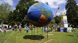 People gather around a giant globe during a climate demonstration at Kimberley Park in Falmouth, Cornwall, England, Saturday, June 12, 2021.