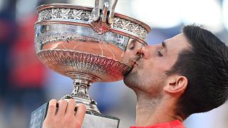 A világelső szerb Novak Djokovic ünnepel a bajnoki trófeával a párizsi Roland Garros Stadionban