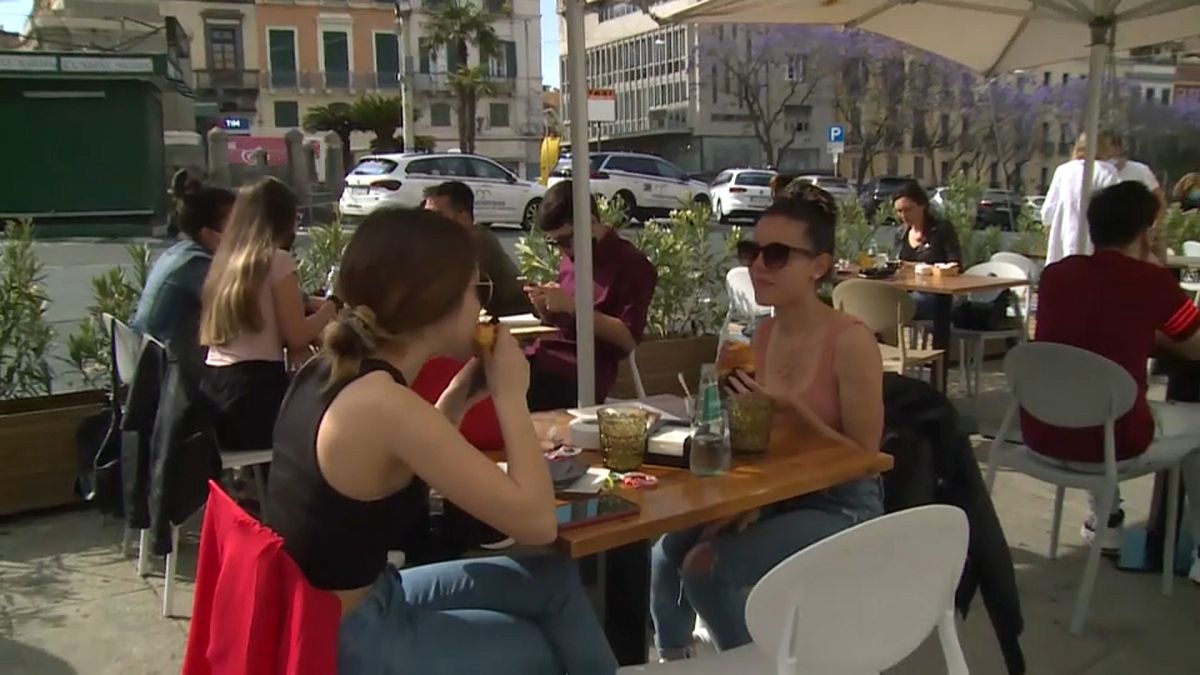 People enjoy a coffee outside in a restaurant in Sardinia, Italy