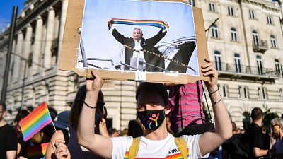 A participant holds a placard showing Hungarian Prime Minister Viktor Orban holding a scarf in rainbow colours, in front of the parliament building in Budapest on June 14