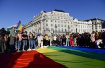 a gente despliega una bandera arco iris durante una manifestación por los derechos LGBT frente al edificio del Parlamento húngaro en Budapest
