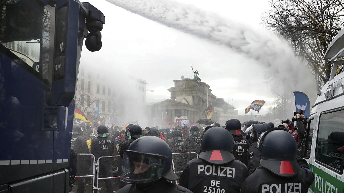 File - In this Wednesday, Nov. 18, 2020 file photo, police uses water canons as people attend a protest rally against coronavirus restrictions in Berlin, Germany. 