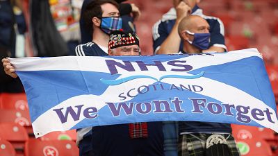 A Scotland supporter holds a Scottish flag with a message in support of the NHS.