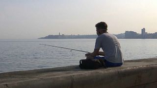 Un joven pesca con caña en el Malecón de La Habana