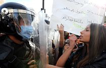 Januári felvétel: kormányellenes tüntető rúzsozza magát egy rohamrendőrrel szemben állva Tuniszban