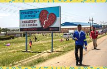 People pass by an AIDS Healthcare Foundation awareness billboard in Maputsoe, Lesotho, on January 31, 2020.
