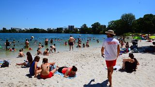 People gather on a sunny afternoon as rescuer walks on the beach of the Lake of Bordeaux, south-western France.