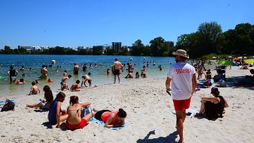 People gather on a sunny afternoon as rescuer walks on the beach of the Lake of Bordeaux, south-western France.