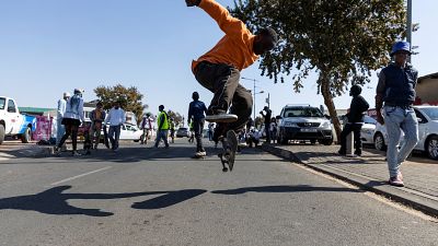 Soweto-Skateboarder surfen die Straße hinunter