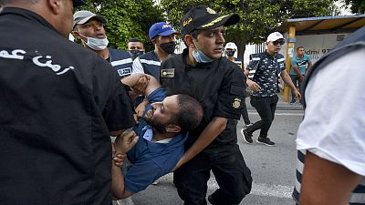 الشرطة التونسية تعتقل متظاهراً خلال احتجاجات ضد عنف الشرطة في شارع الحبيب بورقيبة بالعاصمة تونس، 12 حزيران/يونيو2021 