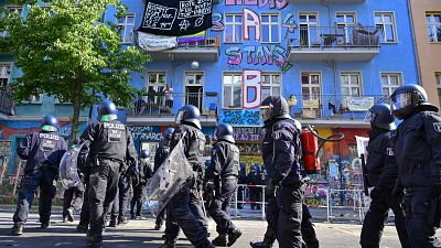 People stand on a balcony as police prepares to enter a building in Rigaer Strasse street in Berlin.