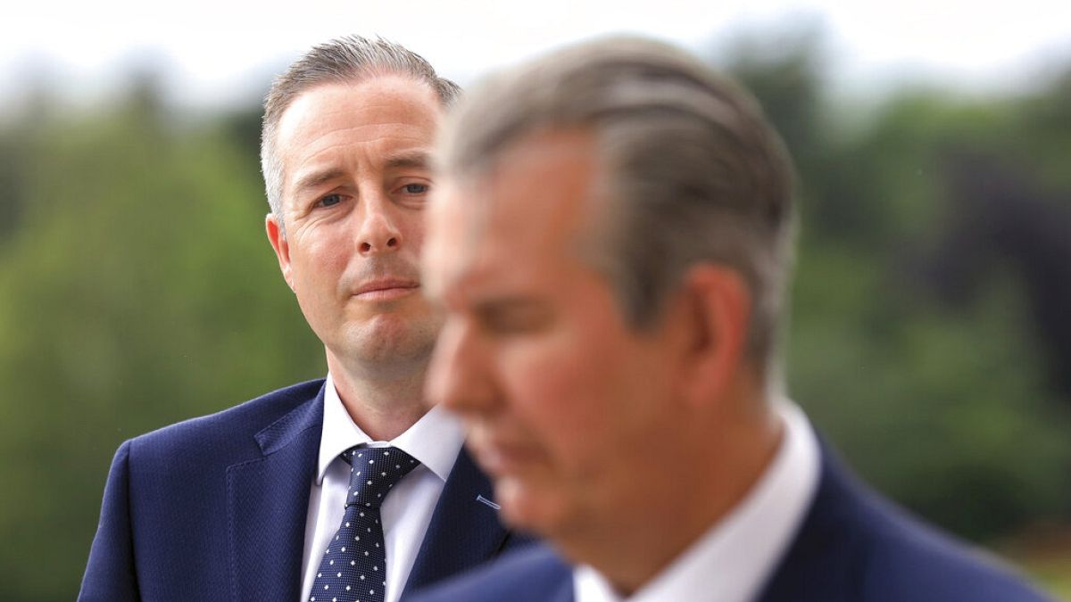 In this Tuesday, June 8, 2021 file photo, Democratic Unionist Party member Paul Givan, background, looks at party leader Edwin Poots during a press conference at Stormont.