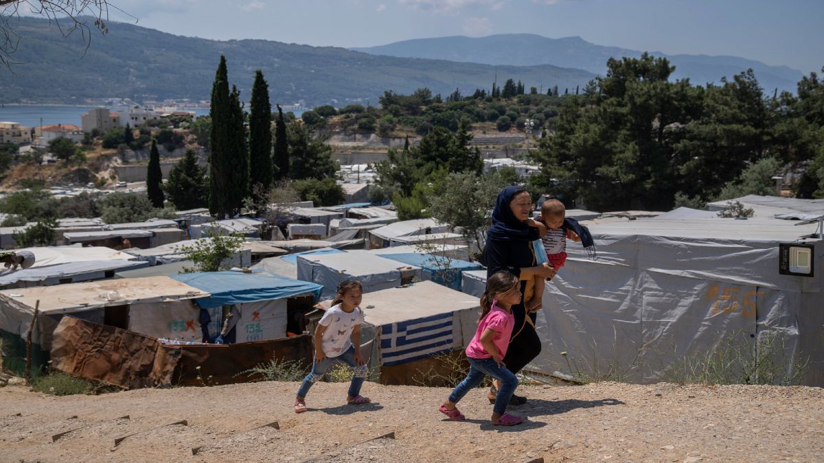 امرأة وأطفالها عند مخيم للاجئين في جزيرة ساموس اليونانية