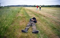 Two participants of an illegal rave party cross a field and one lies, in Redon, north-western France, on June 19, 2021, as French gendarmes intervene to disperse the event