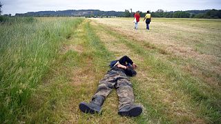 Two participants of an illegal rave party cross a field and one lies, in Redon, north-western France, on June 19, 2021, as French gendarmes intervene to disperse the event