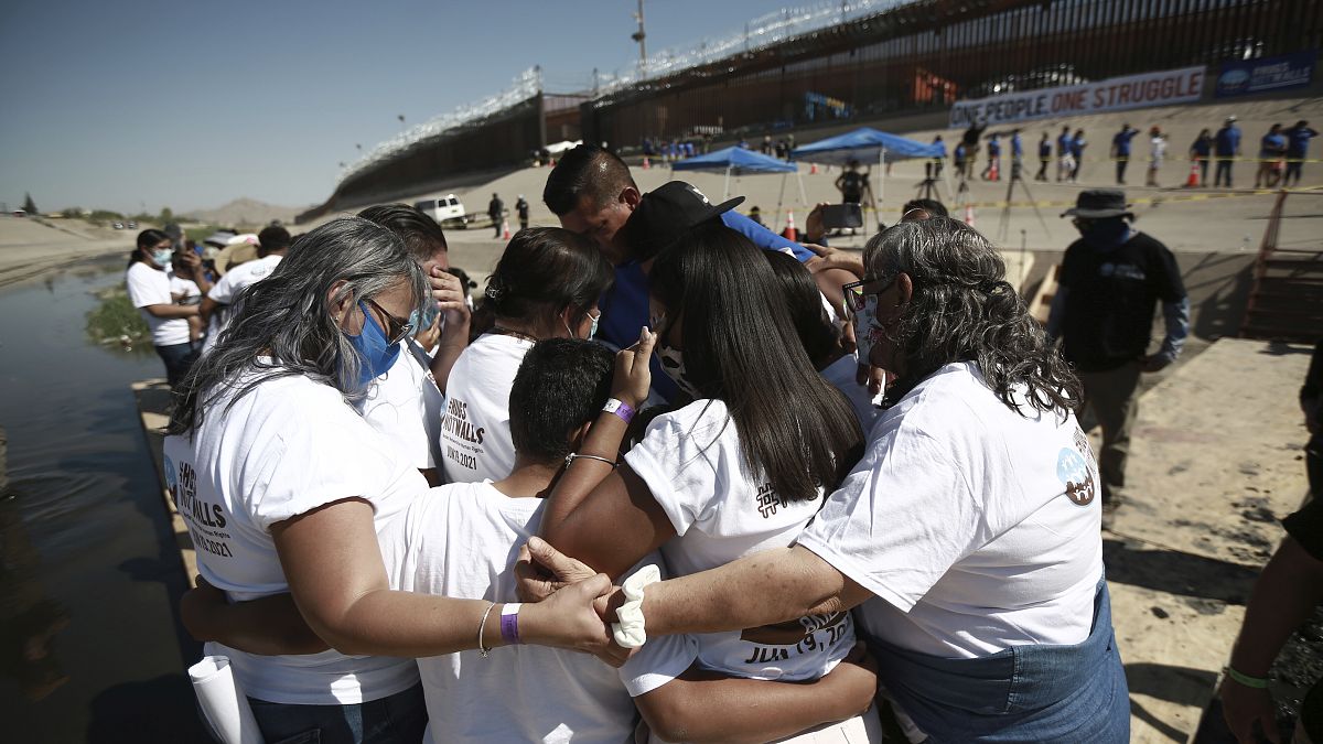 Miembros de una familia migrante se abrazan tras reencontrarse en la frontera 