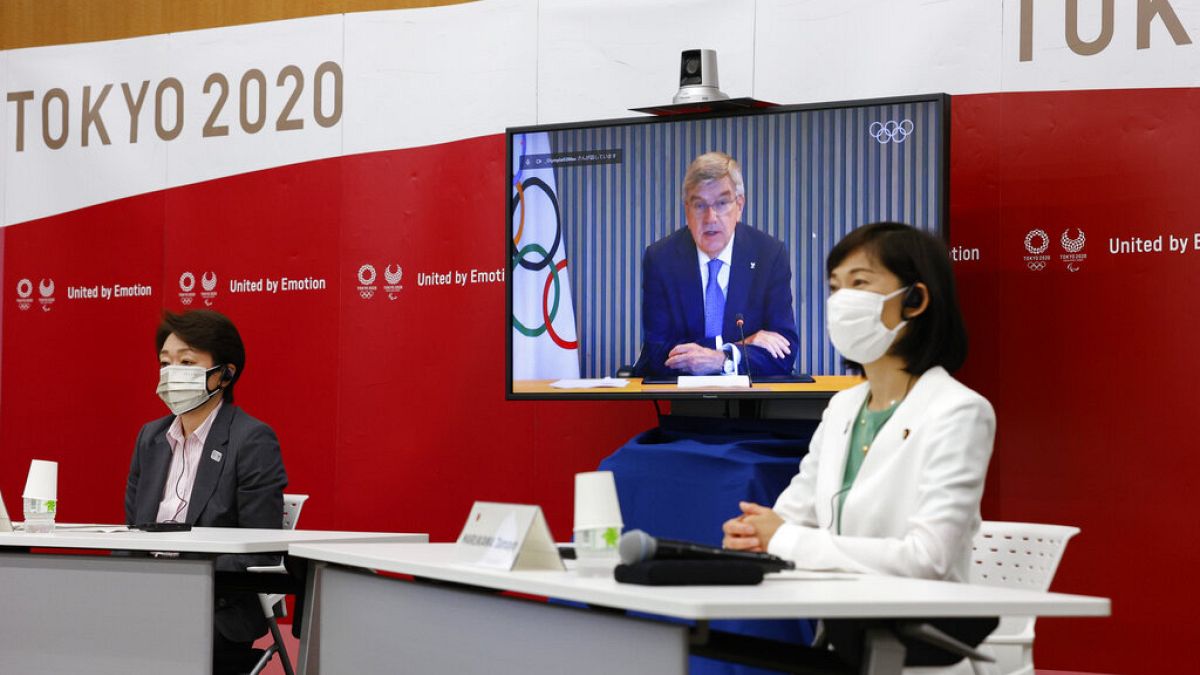 A Tokyo 2020 elnöke, Seiko Hashimoto (b), a japán olimpiai miniszter, Tamayo Marukawa (j) és az IOC elnöke, Thomas Bach egy képernyőn meeting közben. 